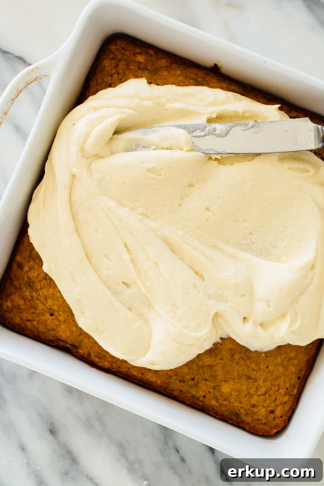 spreading cream cheese frosting on banana cake