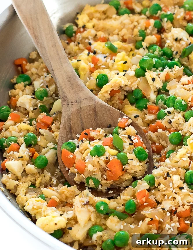 Cauliflower Fried Rice Stir Fry in a pan with a wooden spoon.