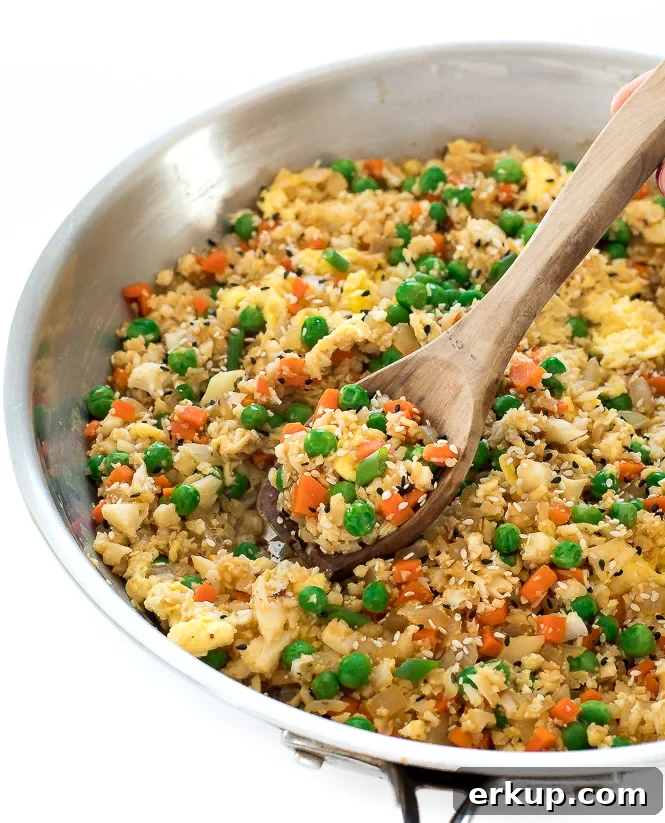 Cauliflower Fried Rice Stir Fry in a pan with a wooden spoon.
