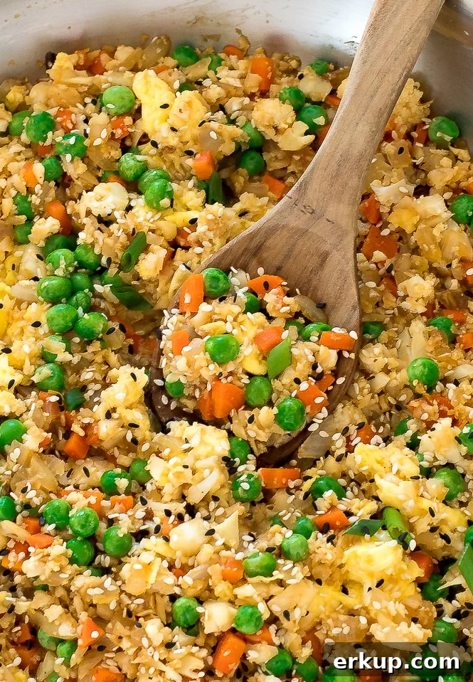 Cauliflower Fried Rice Stir Fry in a pan with a wooden spoon.