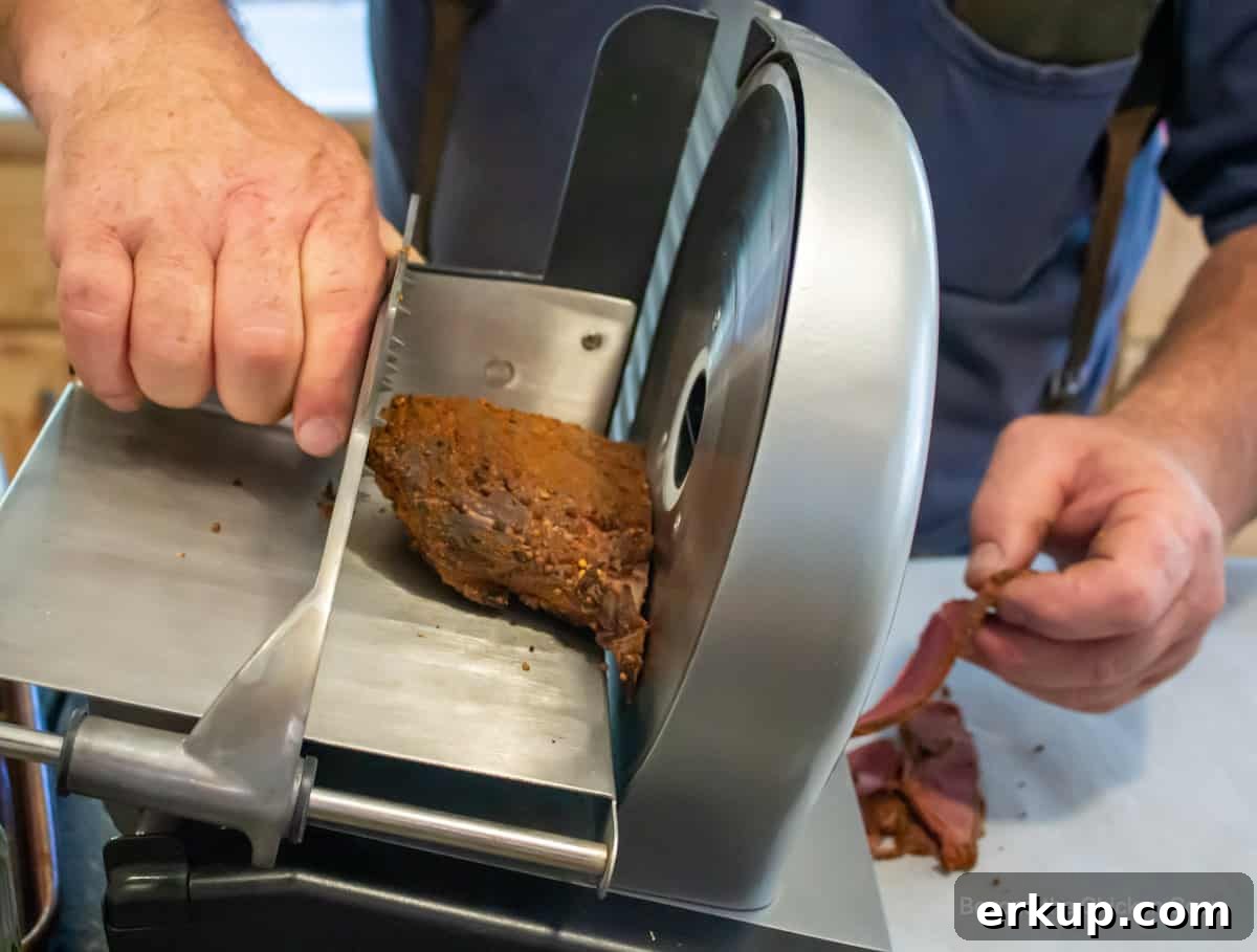 A meat slicer slicing venison pastrami.