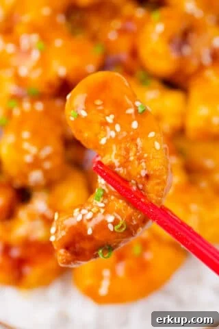 Holding PF Chang's crispy honey shrimp with chopsticks.