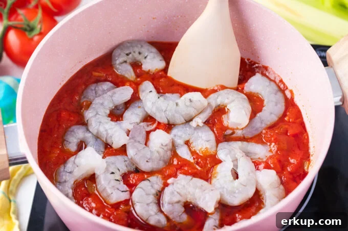 Adding shrimp to Creole tomato sauce.