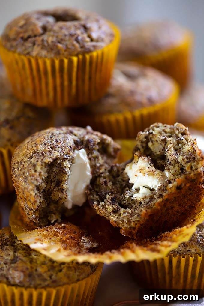 Close up of split Chocolate Cream Cheese Muffin with more muffins stacked in the background