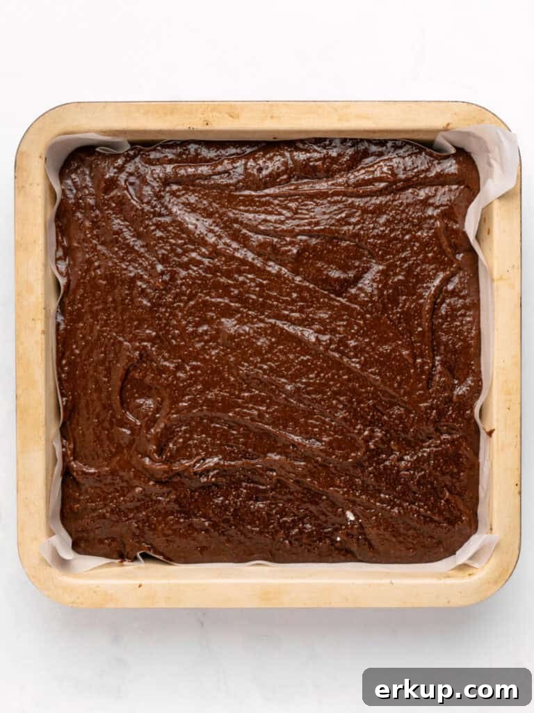 Square pan with brownie batter. White background.