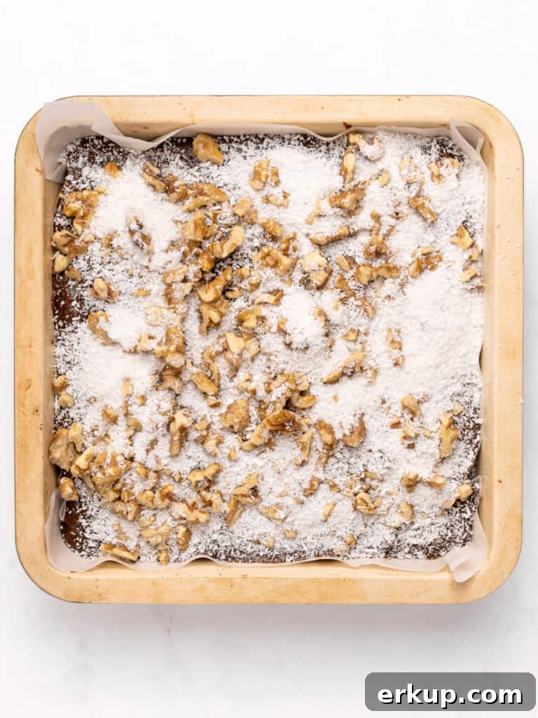 Walnuts and coconut sprinkled over brownie batter in the pan.