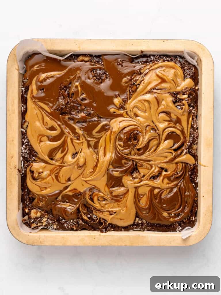 Marbled peanut butter, dulce de leche and brownie batter in a square pan. White background.