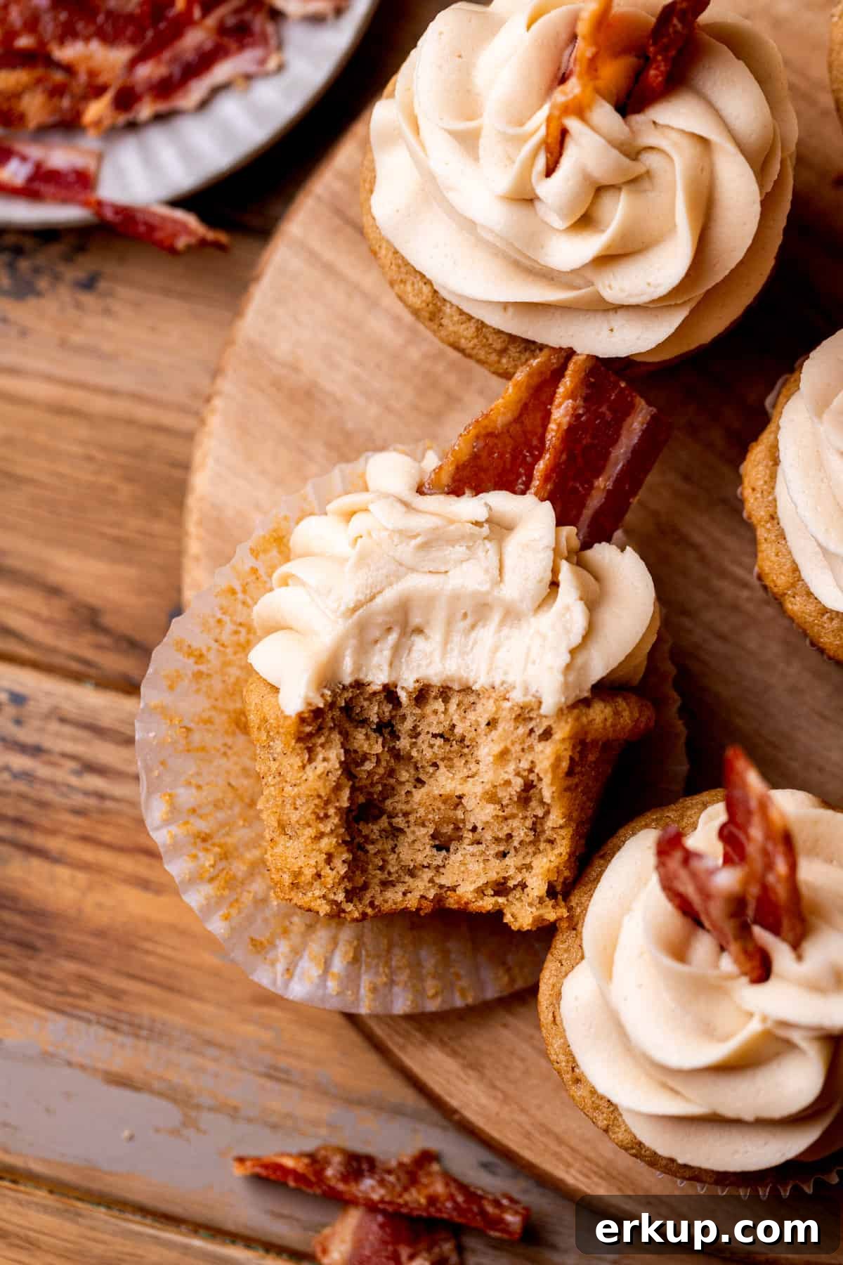Maple Bacon Cupcakes with Candied Bacon 2 Top view of a maple bacon cupcake with a bite missing.