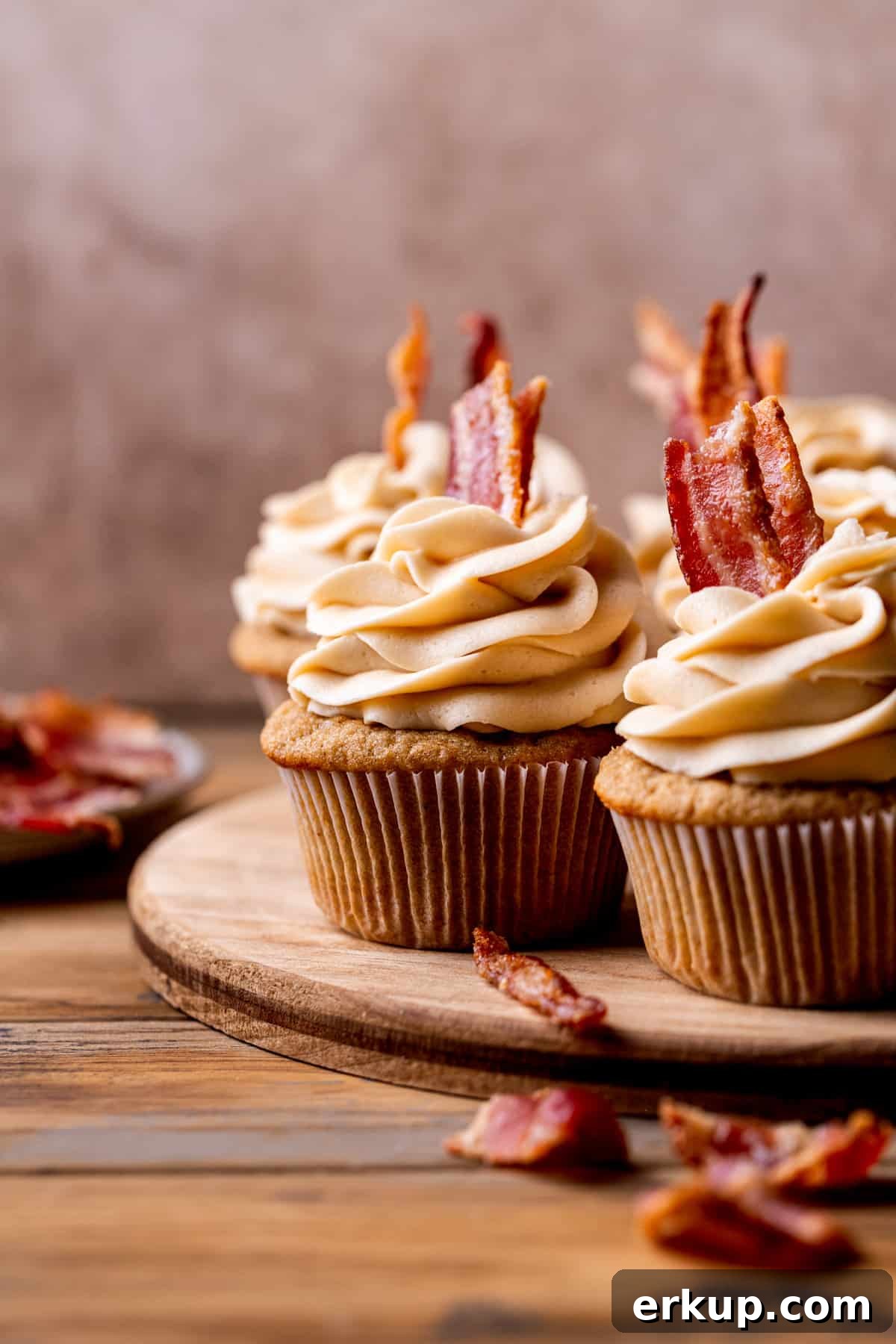 Maple Bacon Cupcakes with Candied Bacon 10 Decorated cupcakes on a wood board.