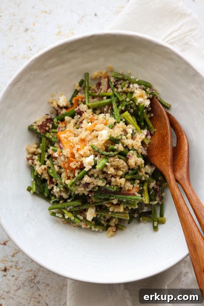 warm quinoa salad in bowl with serving utensils