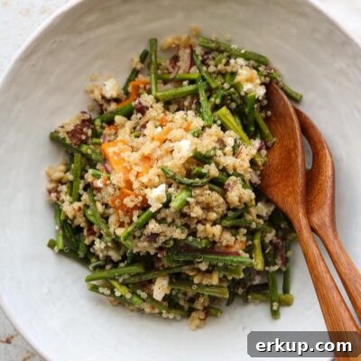 warm quinoa salad in bowl with serving utensils