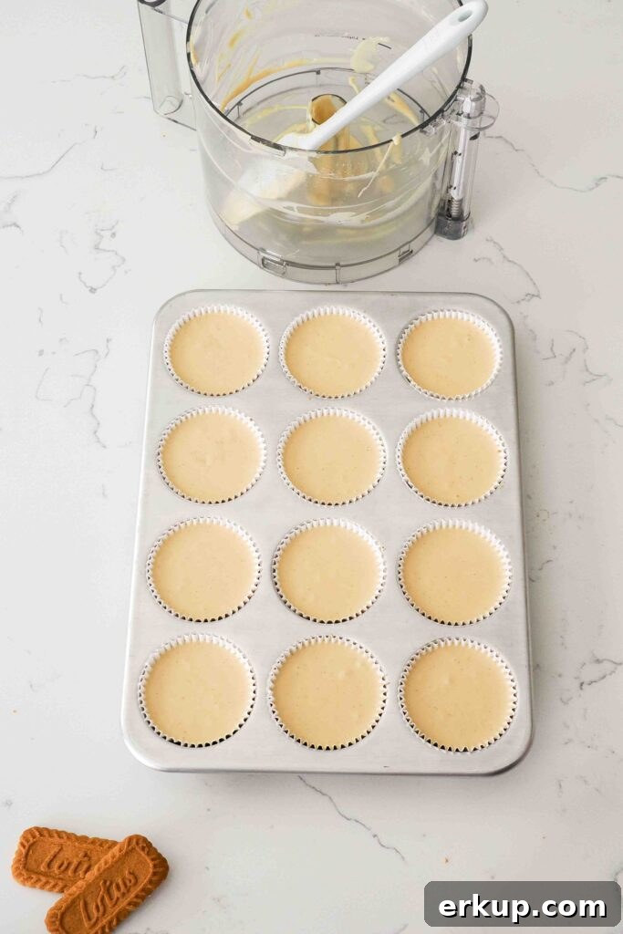 Unbaked Biscoff cheesecakes in a muffin pan.