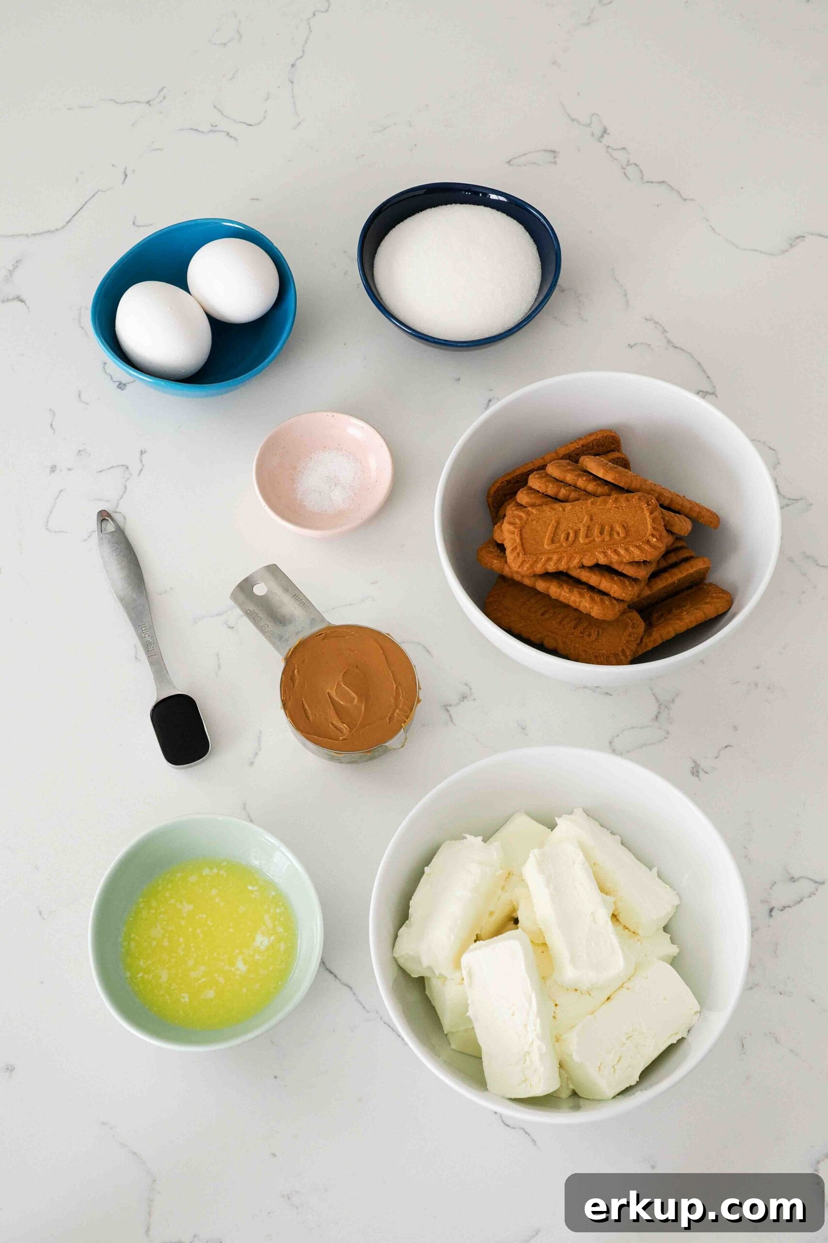 Ingredients for mini Biscoff cheesecakes on a quartz countertop.