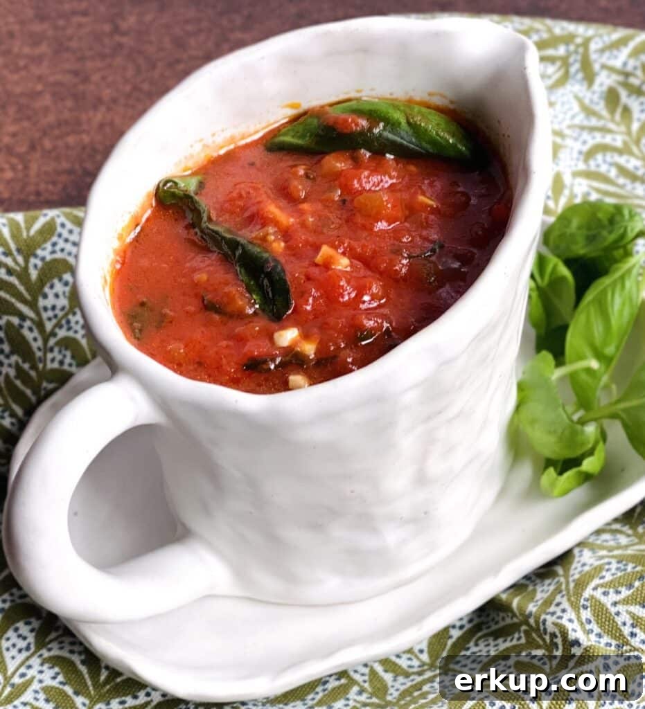 Tomato basil sugo recipe in gravy boat with basil garnish.