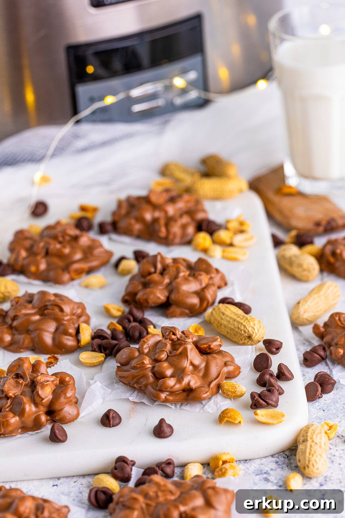 Slow Cooker Peanut Clusters on board with peanuts and chocolate chips surrounding them.