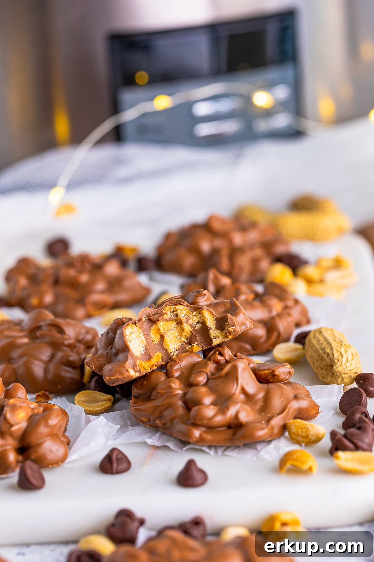 Slow Cooker Peanut Clusters on white board with one stacked with bite taken out of it.
