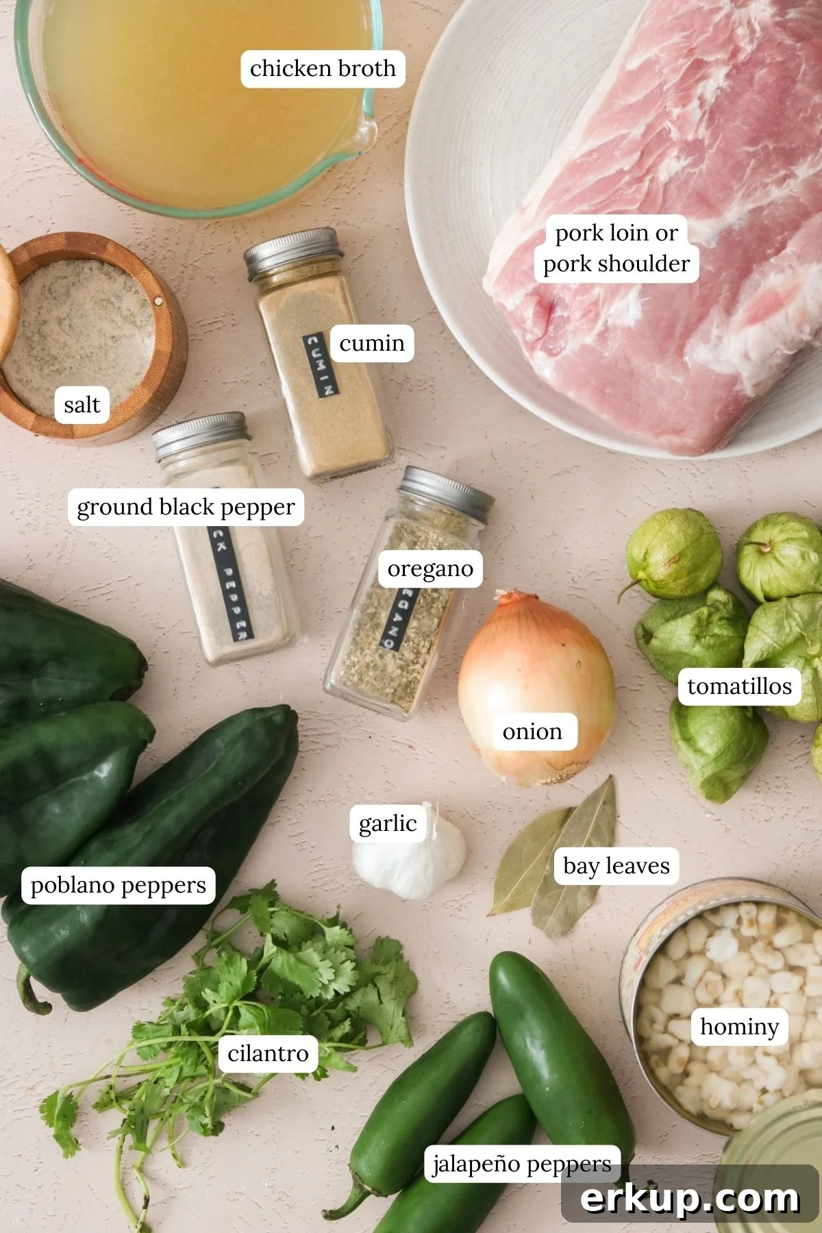 Pozole verde ingredients in small bowls, including tomatillos, poblano peppers, jalapeños, garlic, onion, spices, and hominy