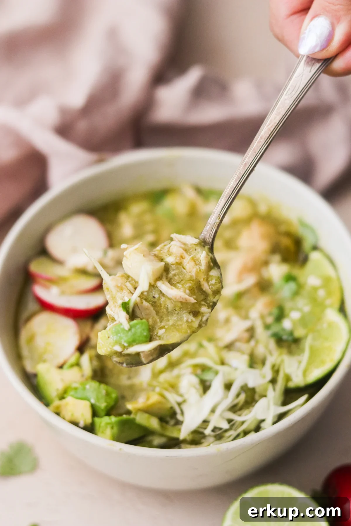 Spoonful of pozole verde showing tender pork, hominy, and green broth.
