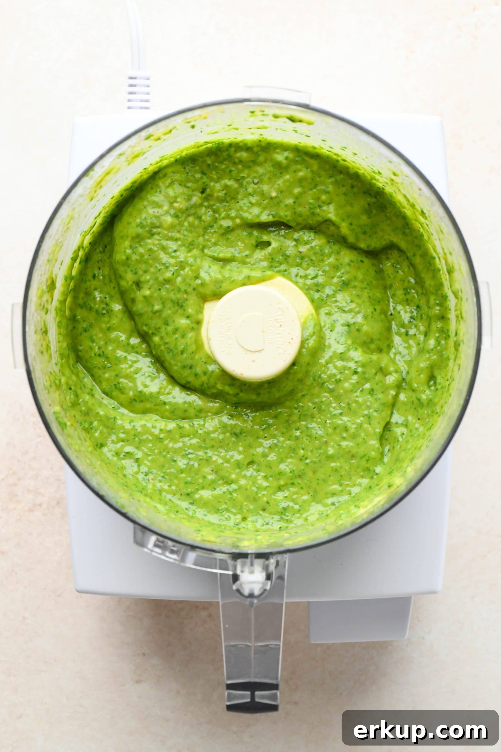 How to make avocado herb green sauce: Sauce processed together in the bowl of a food processor.