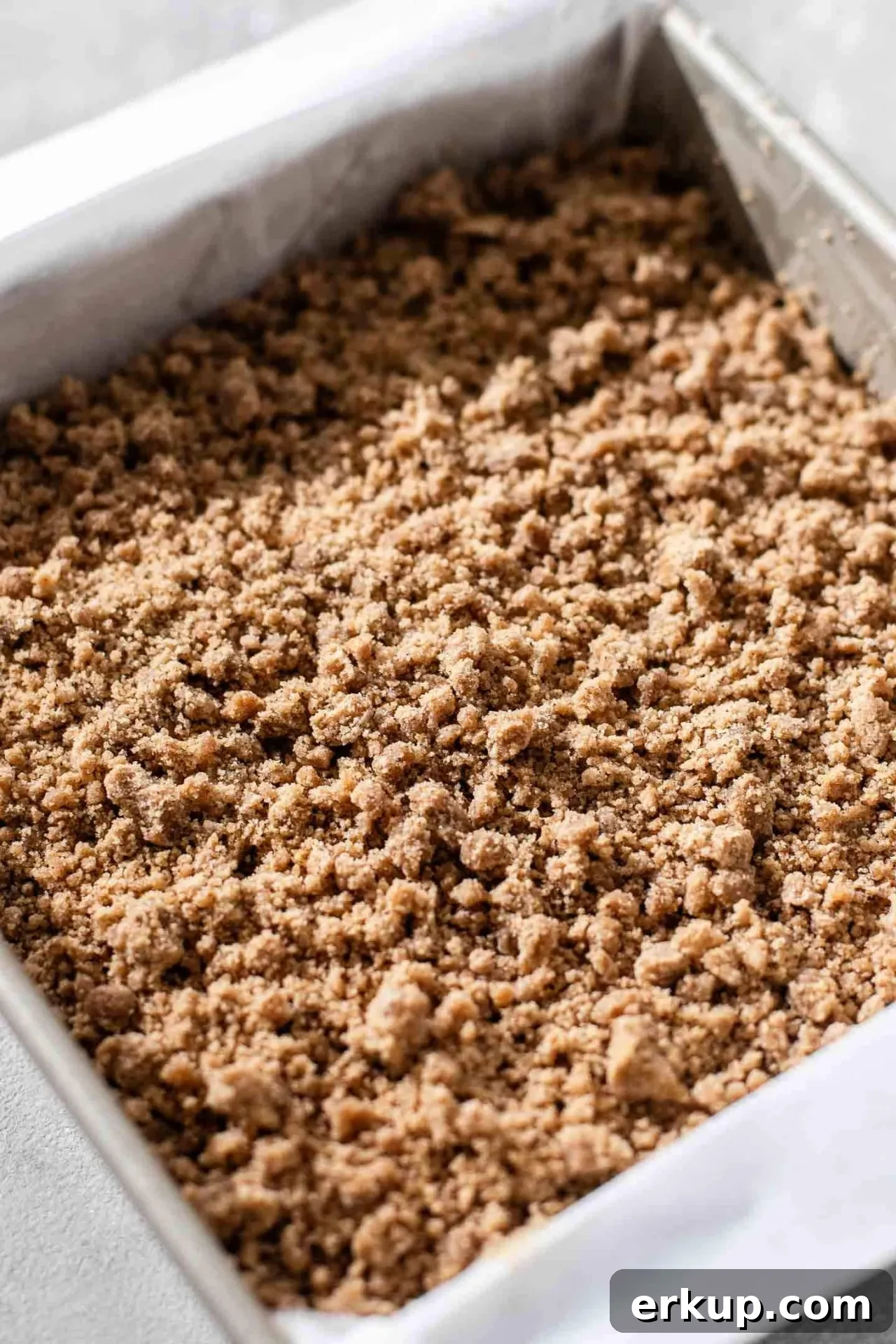 sour cream zucchini coffee cake streusel sprinkled on top of cake batter in baking pan