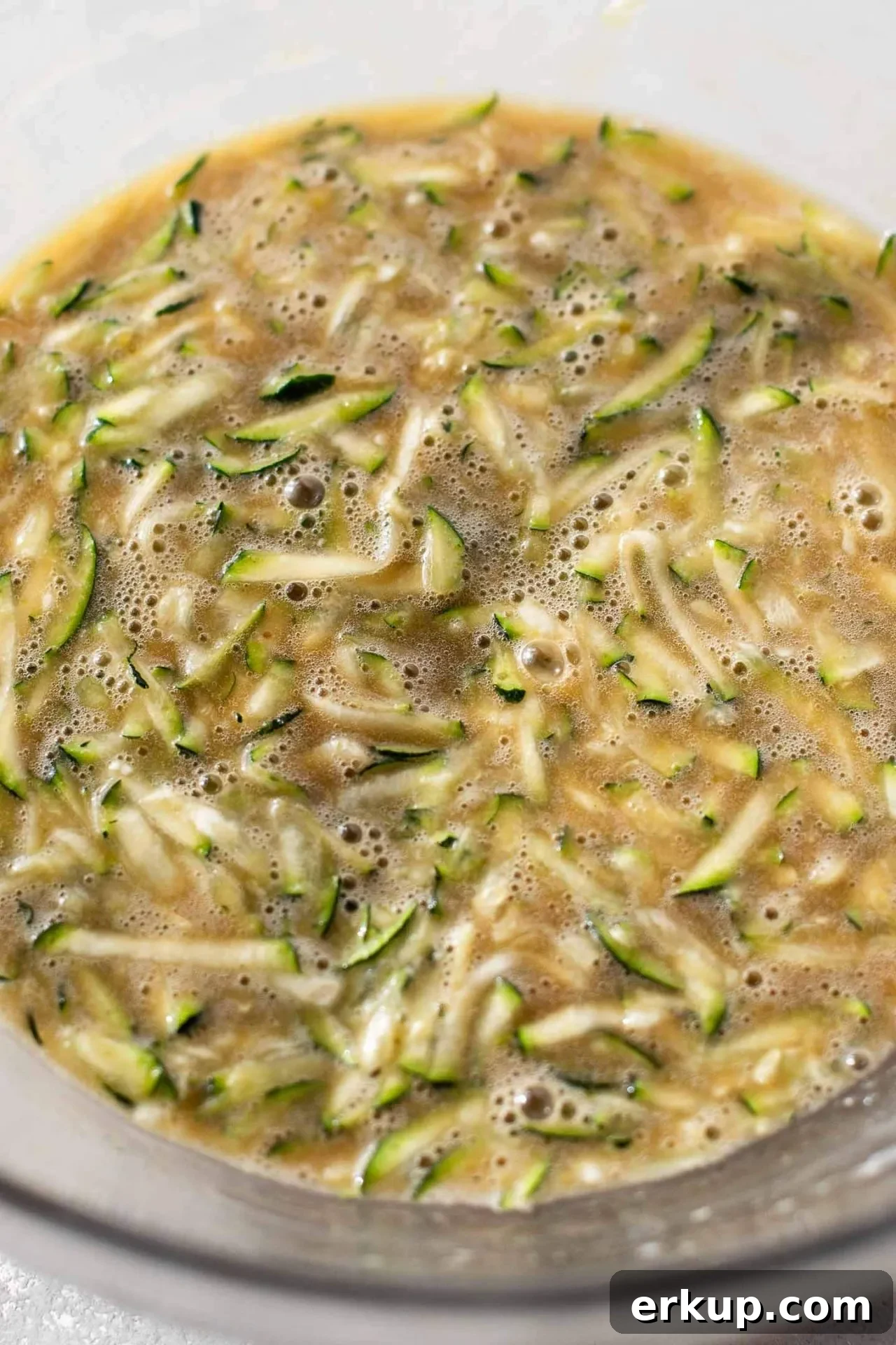 sour cream zucchini coffee cake zucchini mixed into bowl with wet ingredients