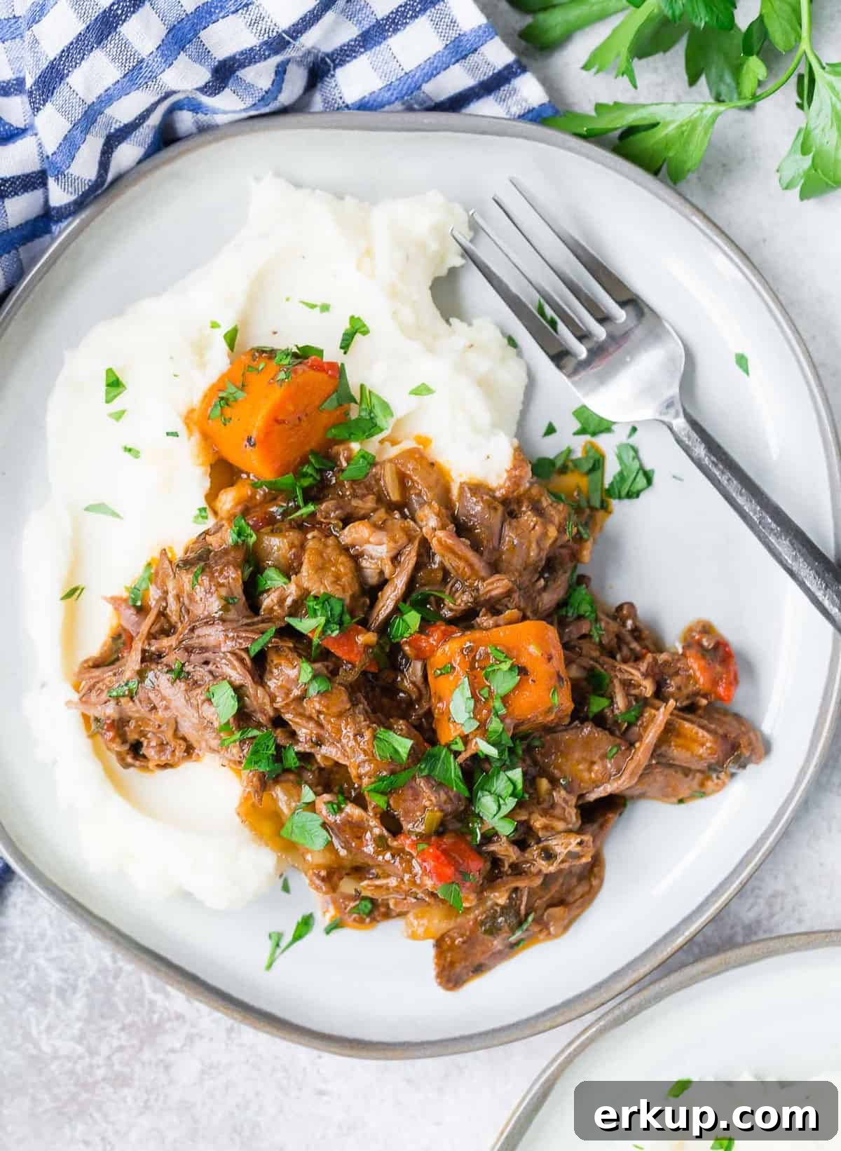 Overhead view of pot roast on top of potatoes.