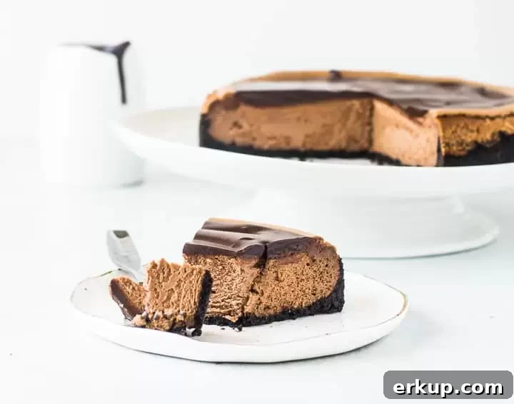slice of triple chocolate cheesecake on a plate with the rest of the cake in the background