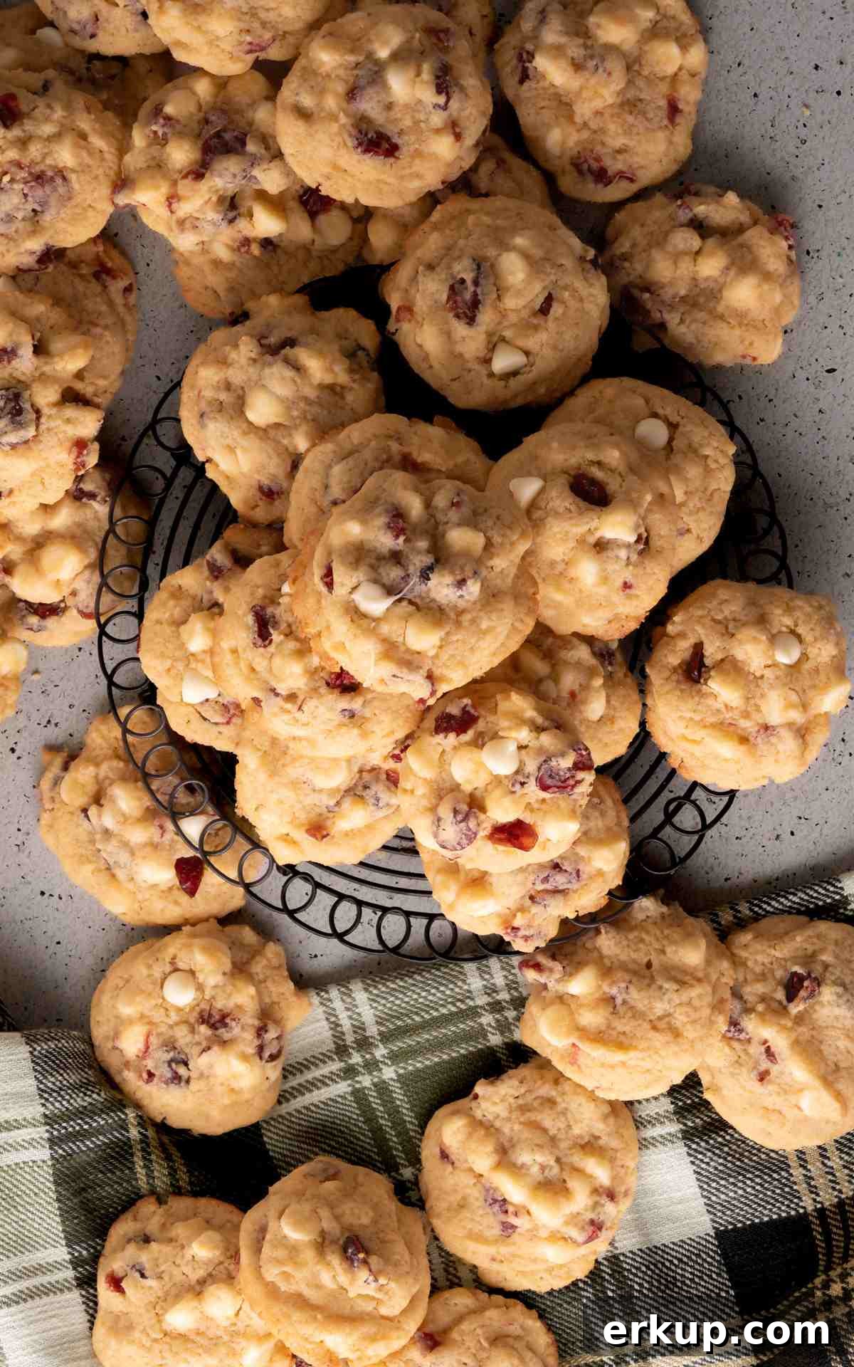 Overhead of white chocolate cranberry cookies on a wire rack and counter.