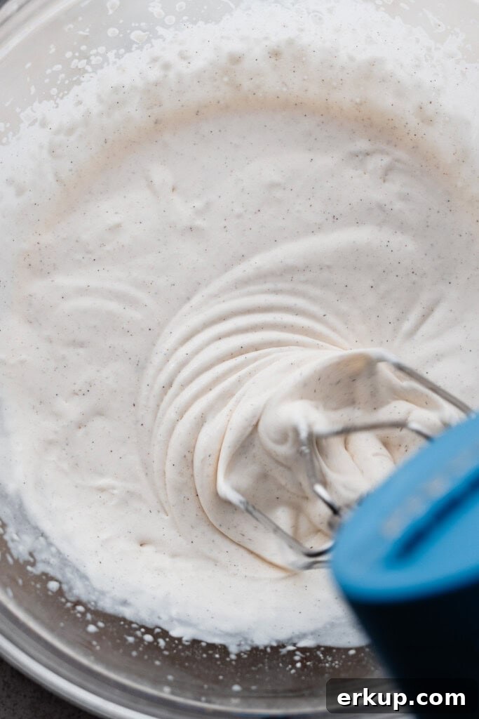 The whipped cream being whipped with a mixer.