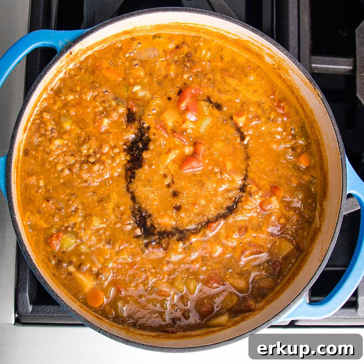 Blended lentil soup in a blue dutch oven, with a swirl of balsamic on top. 