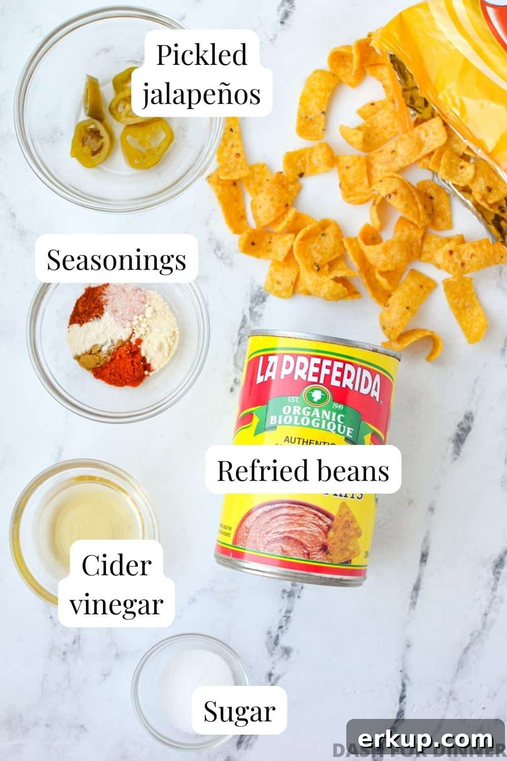 The ingredients needed to make bean dip: refried beans, seasoning, cider vinegar, sugar, and jalapeno slices.