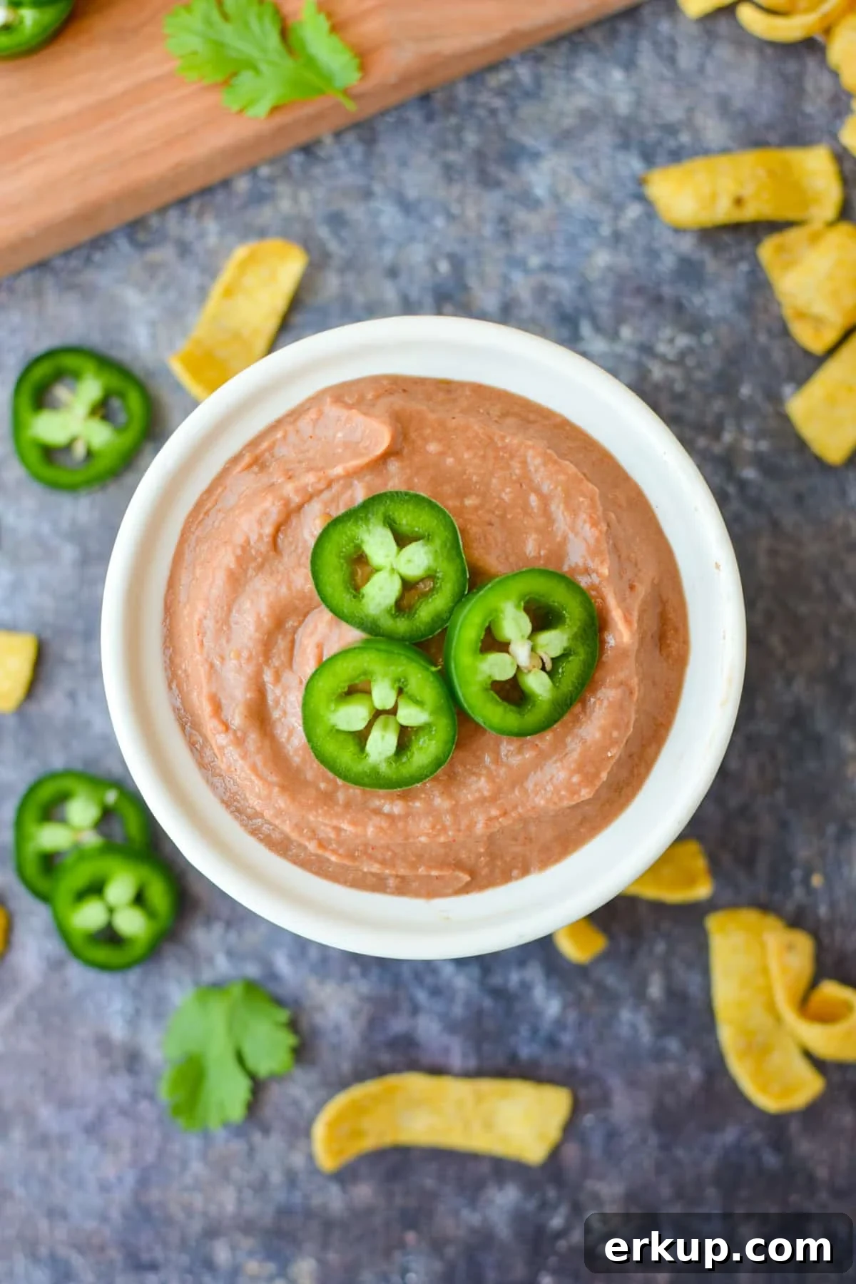 A bowl of bean dip garnished with jalapeno slices on top.
