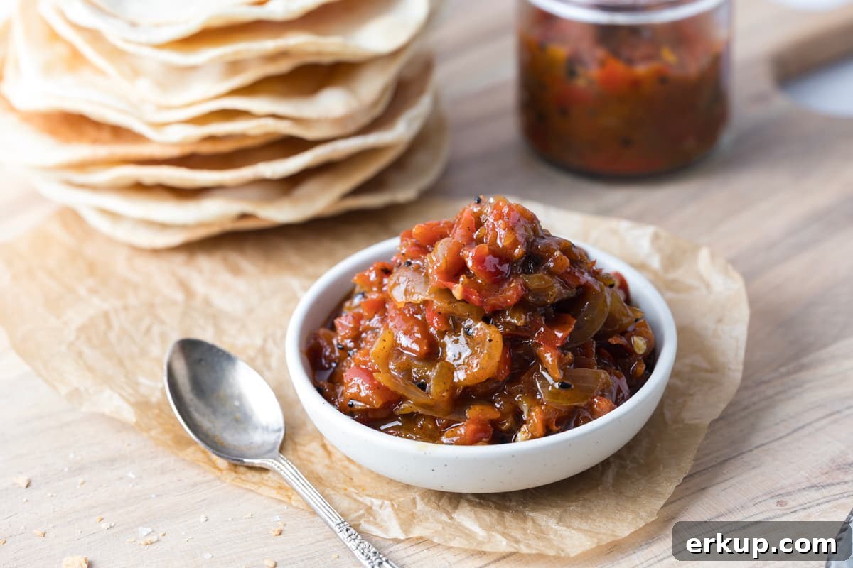 Homemade Sweet and Spicy Red Pepper Relish Recipe 2 A bowl of red pepper relish on a serving tray next to a spoon to be served atop of sourdough crackers.