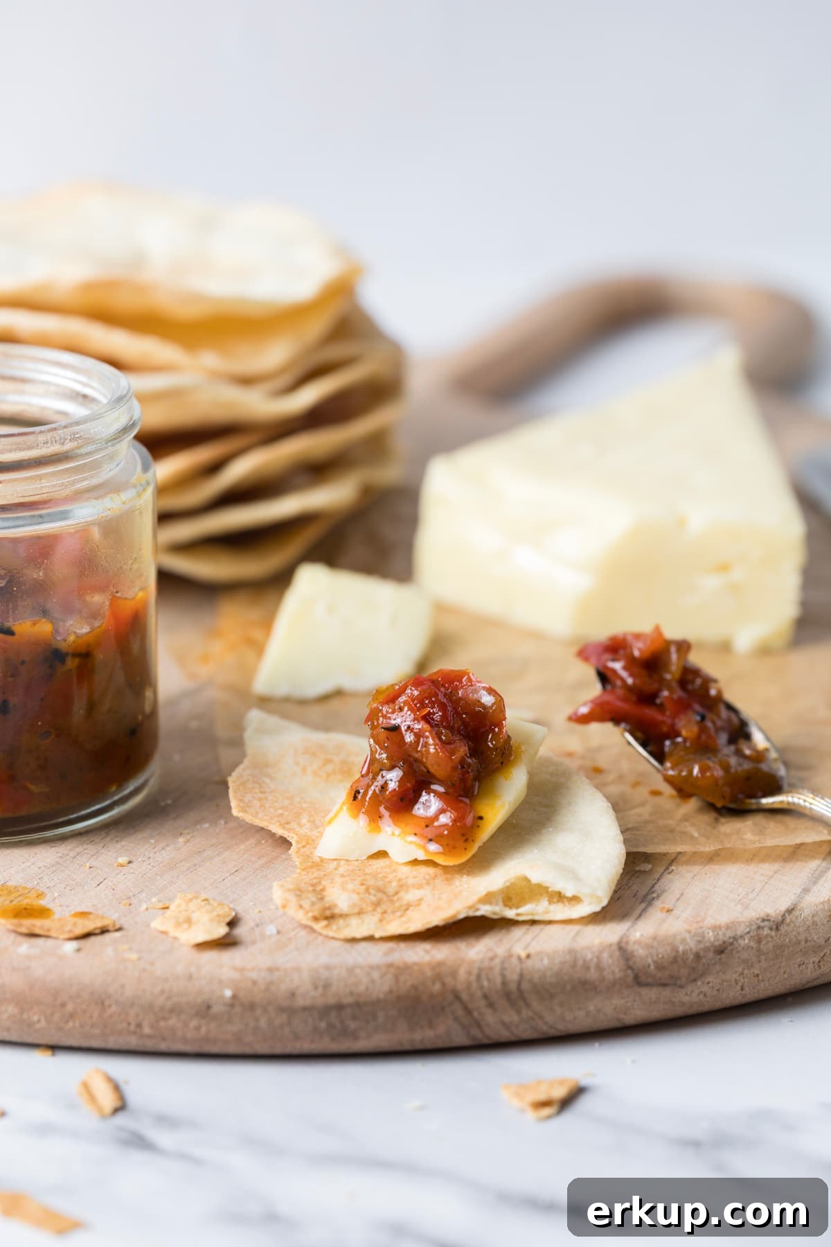 Homemade Sweet and Spicy Red Pepper Relish Recipe 3 Red pepper relish served on top of a piece of cheese on top of a sourdough cracker.