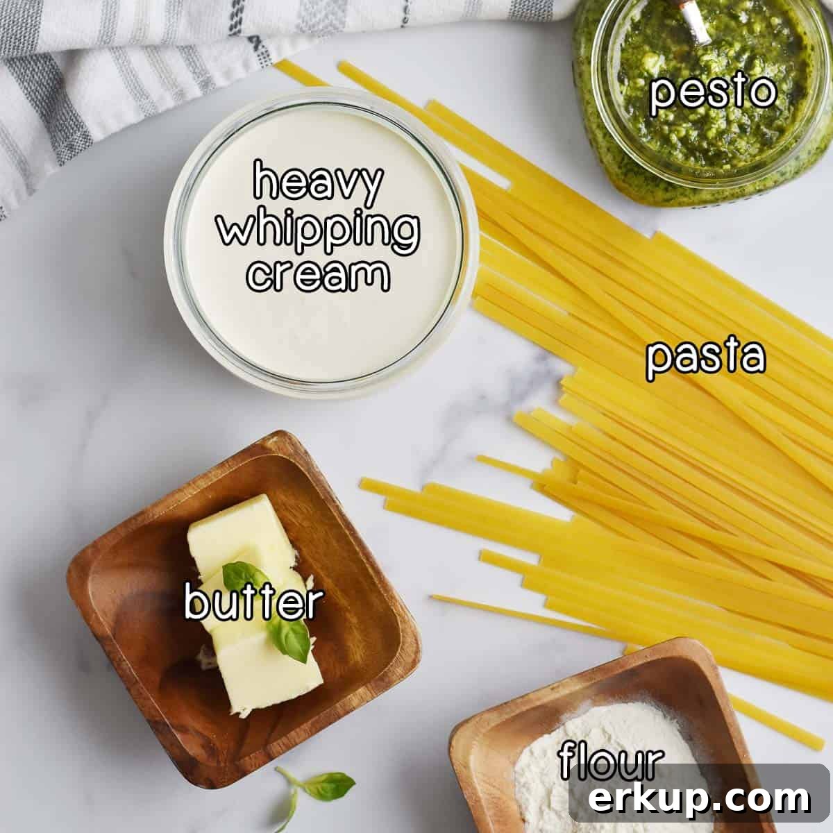 Overhead shot of ingredients - pesto, heavy whipping cream, pasta, butter, and flour.