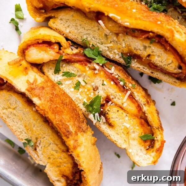 Homemade Stromboli Recipe: Crispy Cheesy Italian Roll 6 Top dow view of slices of stromboli sitting on white piece of parchment paper with parsley and Parmesan cheese on top