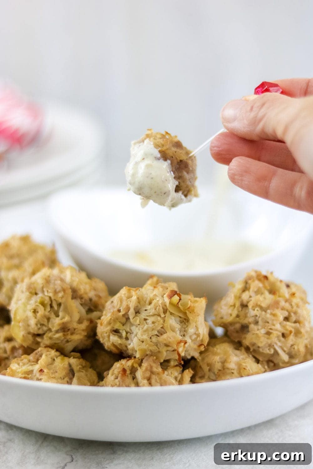 Baked sauerkraut ball being dipped into Creamy Horseradish mustard sauce