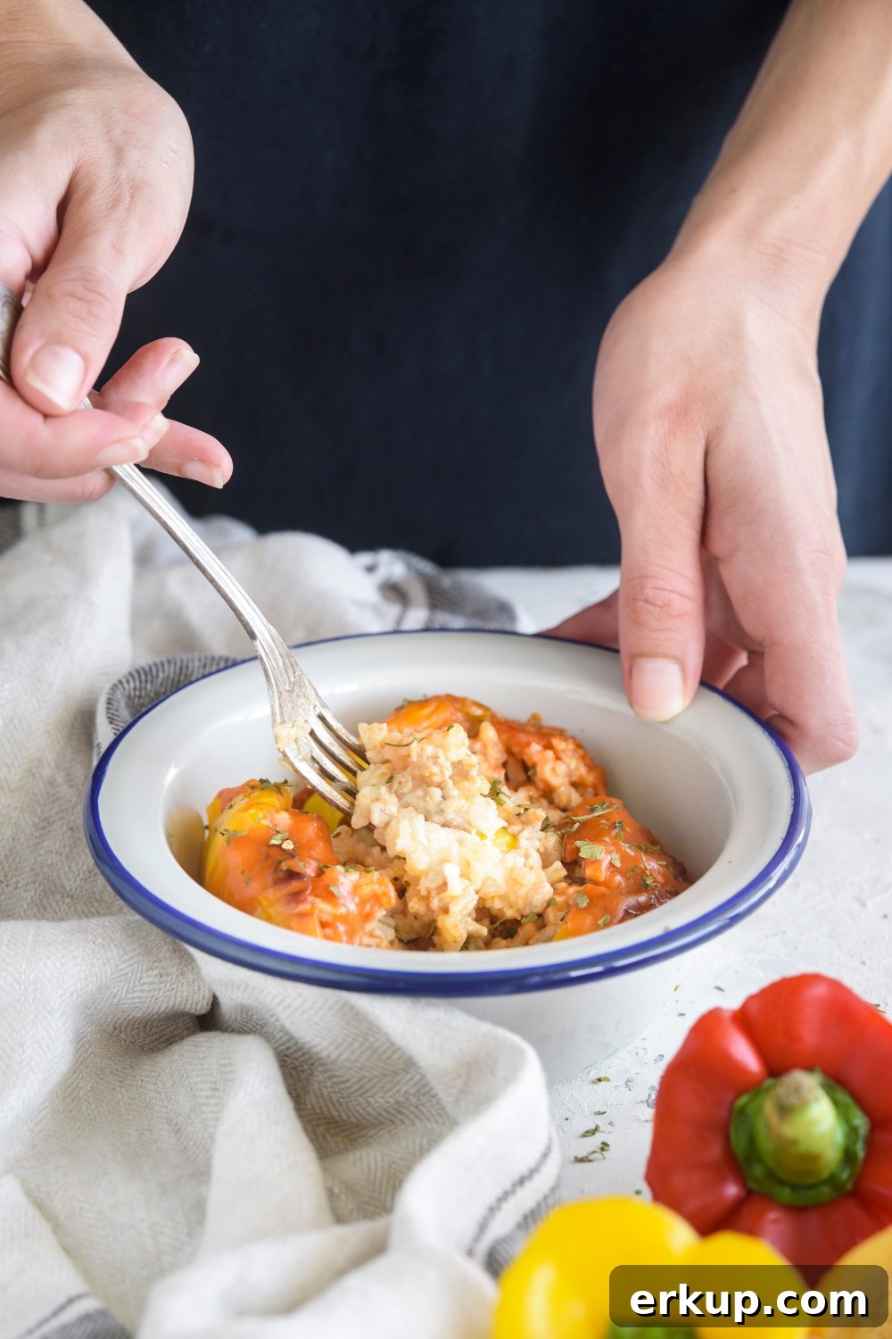 Old-Fashioned Stuffed Bell Peppers Recipe 4 A person using a fork to grab a bite of stuffed bell pepper with rice and ground meat in the pepper.