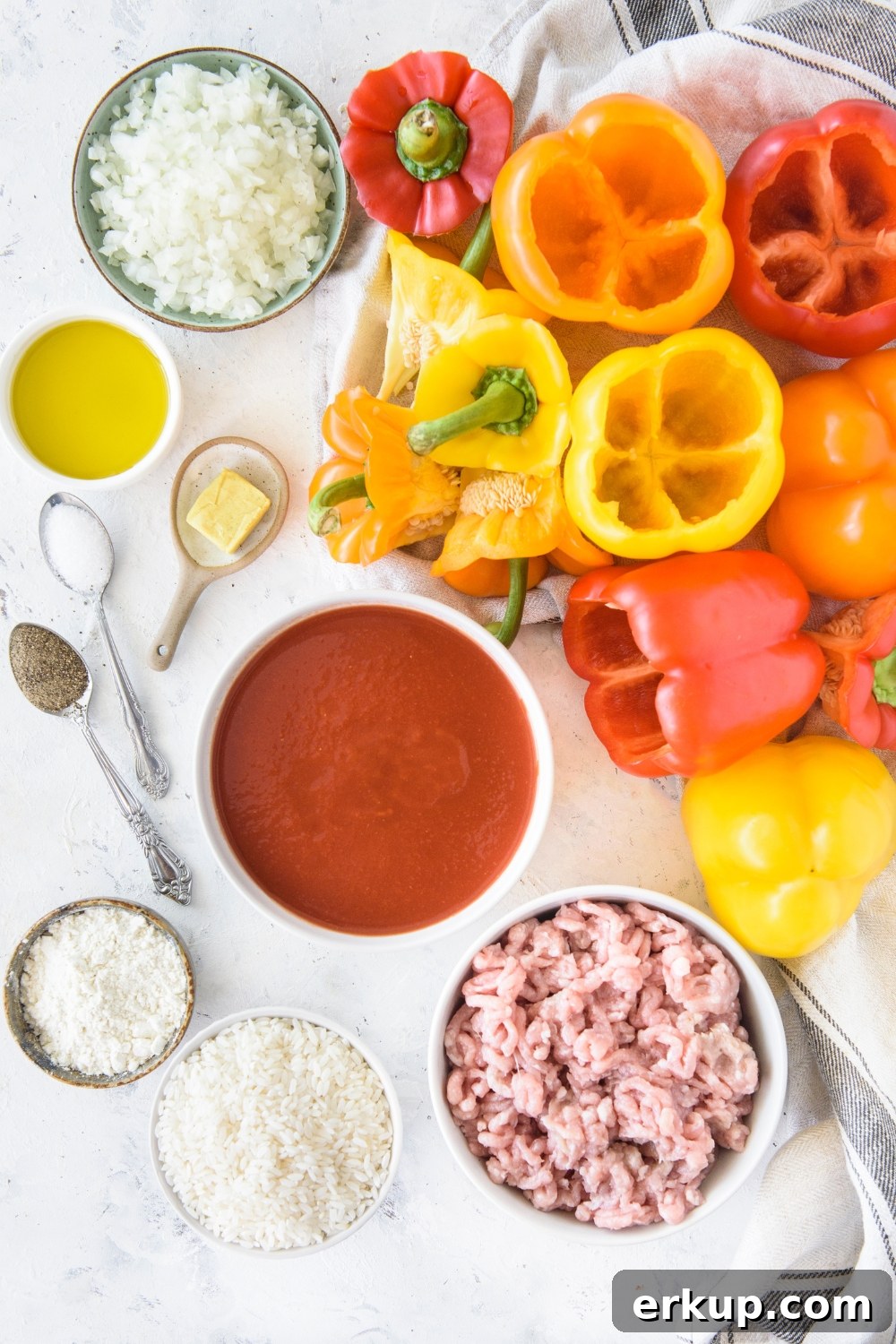 Old-Fashioned Stuffed Bell Peppers Recipe 5 A pile of bell peppers with the seeds and stems removed next to bowls of ingredients including raw ground meat, tomato sauce, flour, oil, diced onion, and butter.