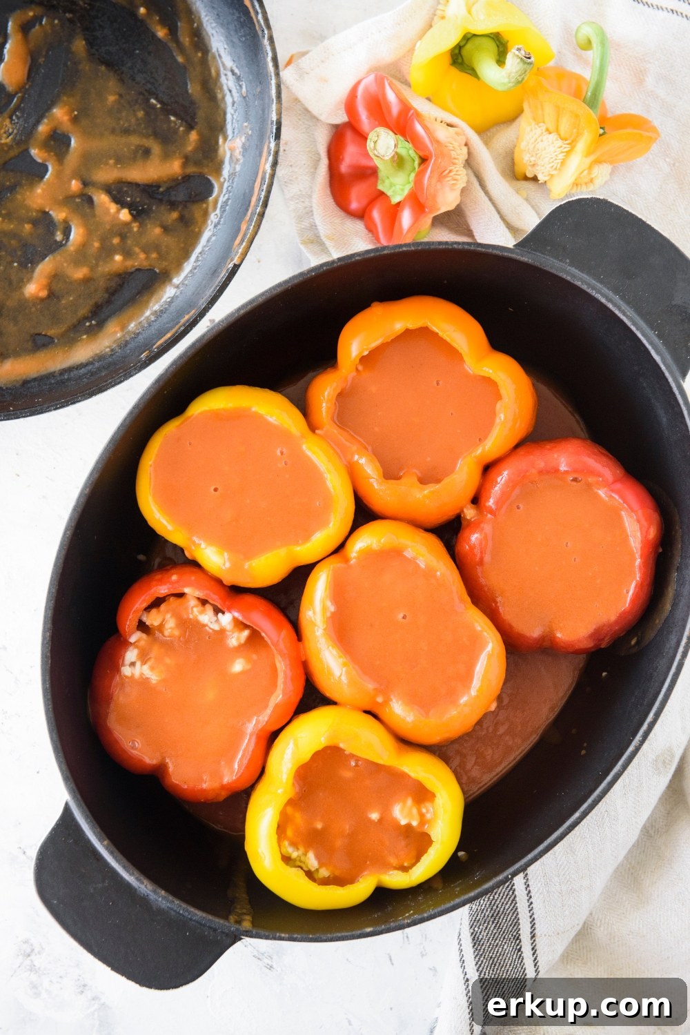 Old-Fashioned Stuffed Bell Peppers Recipe 8 A baking dish filled with bell peppers that have been stuffed with ground meat and rice and each pepper has been topped with tomato sauce.