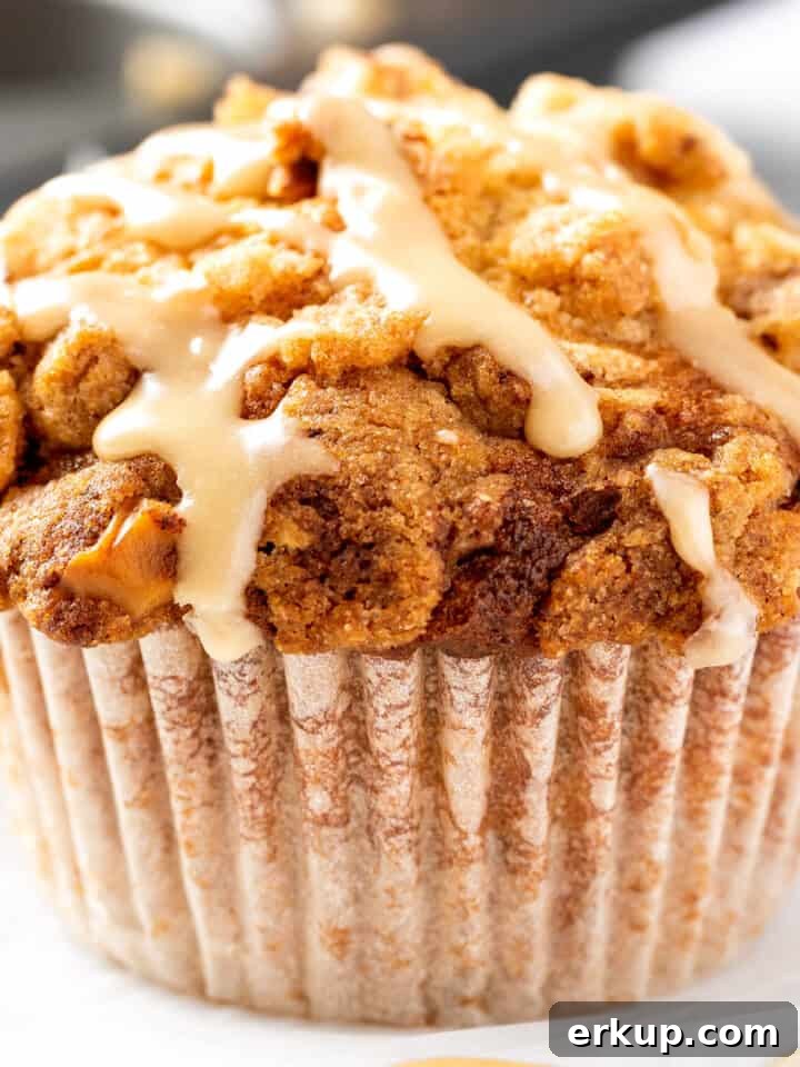A maple walnut muffin drizzled with maple glaze, sitting on white marble table.