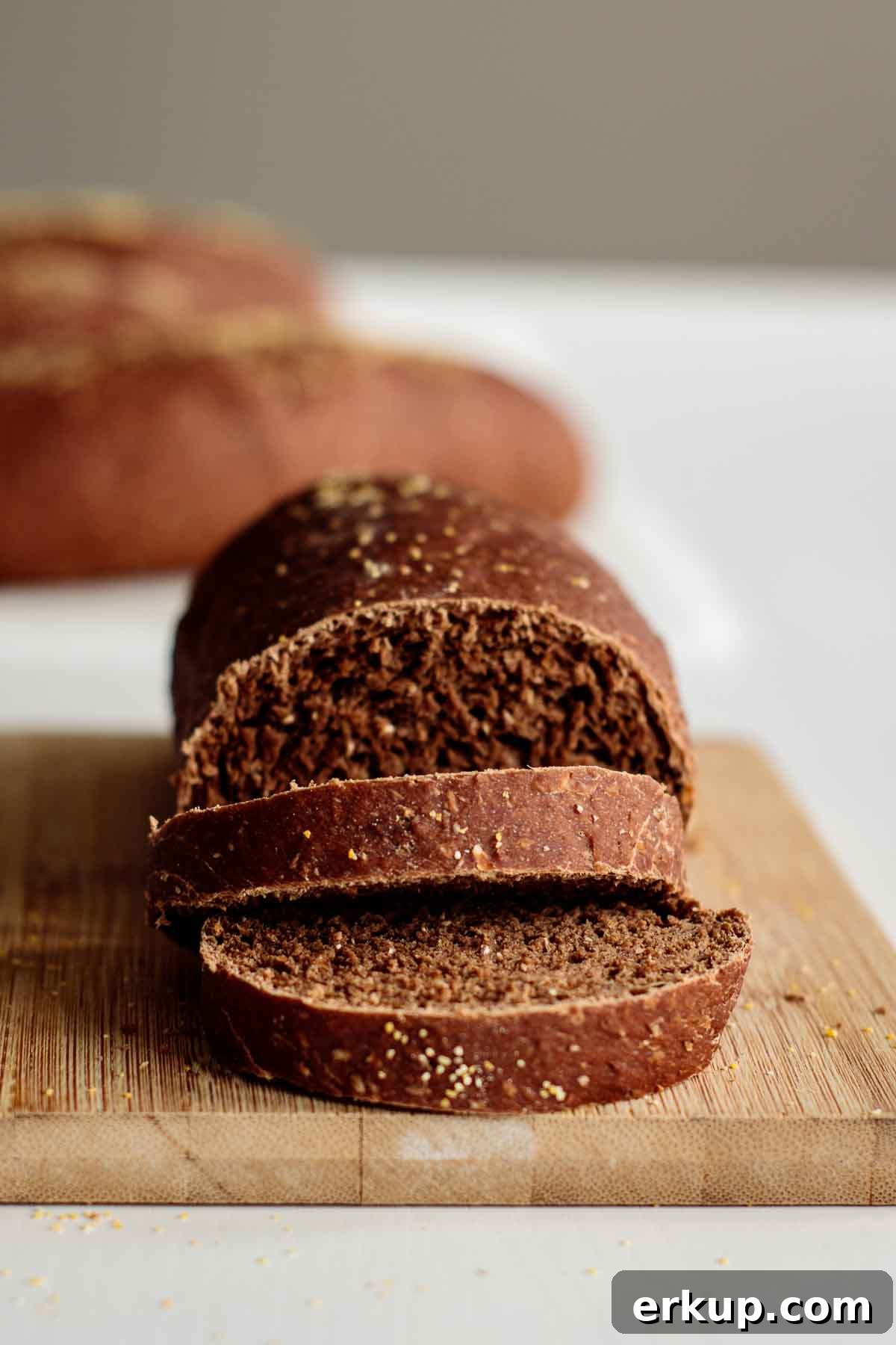 Loaf sliced on the top of a wooden board with outback bread rolls in the background.