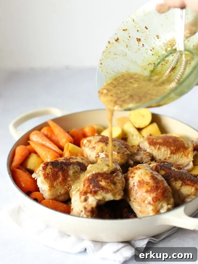 Browned chicken thighs and carrots having sauce poured over.