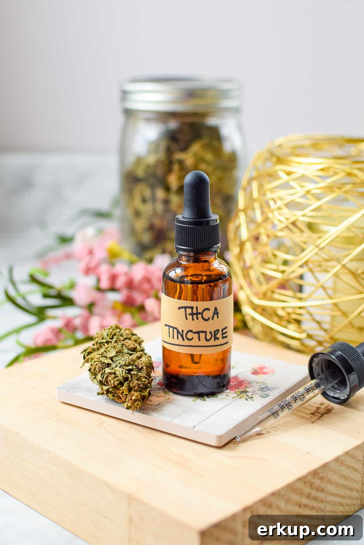 How to Make a THCA Tincture at Home 2 A white countertop with a brown tincture bottle labeled THCA tincture with a cannabis flower bud next to it
