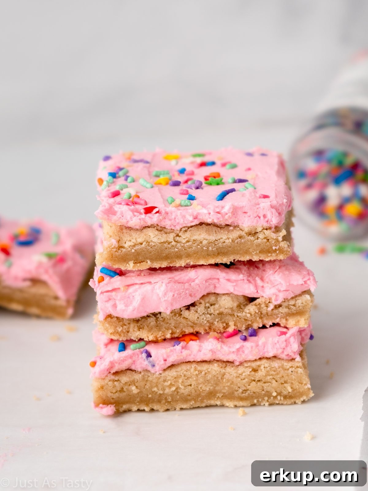 Stack of three pink frosted sugar cookie cake bars. 