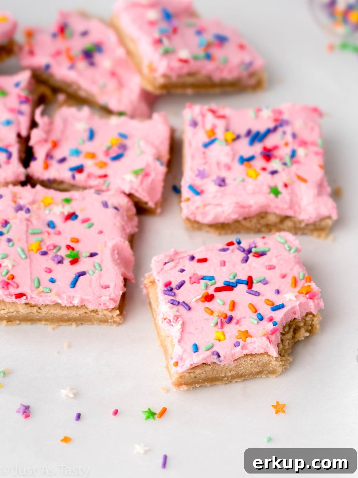 Pink frosted sugar cookie bar with a bite taken out of it.