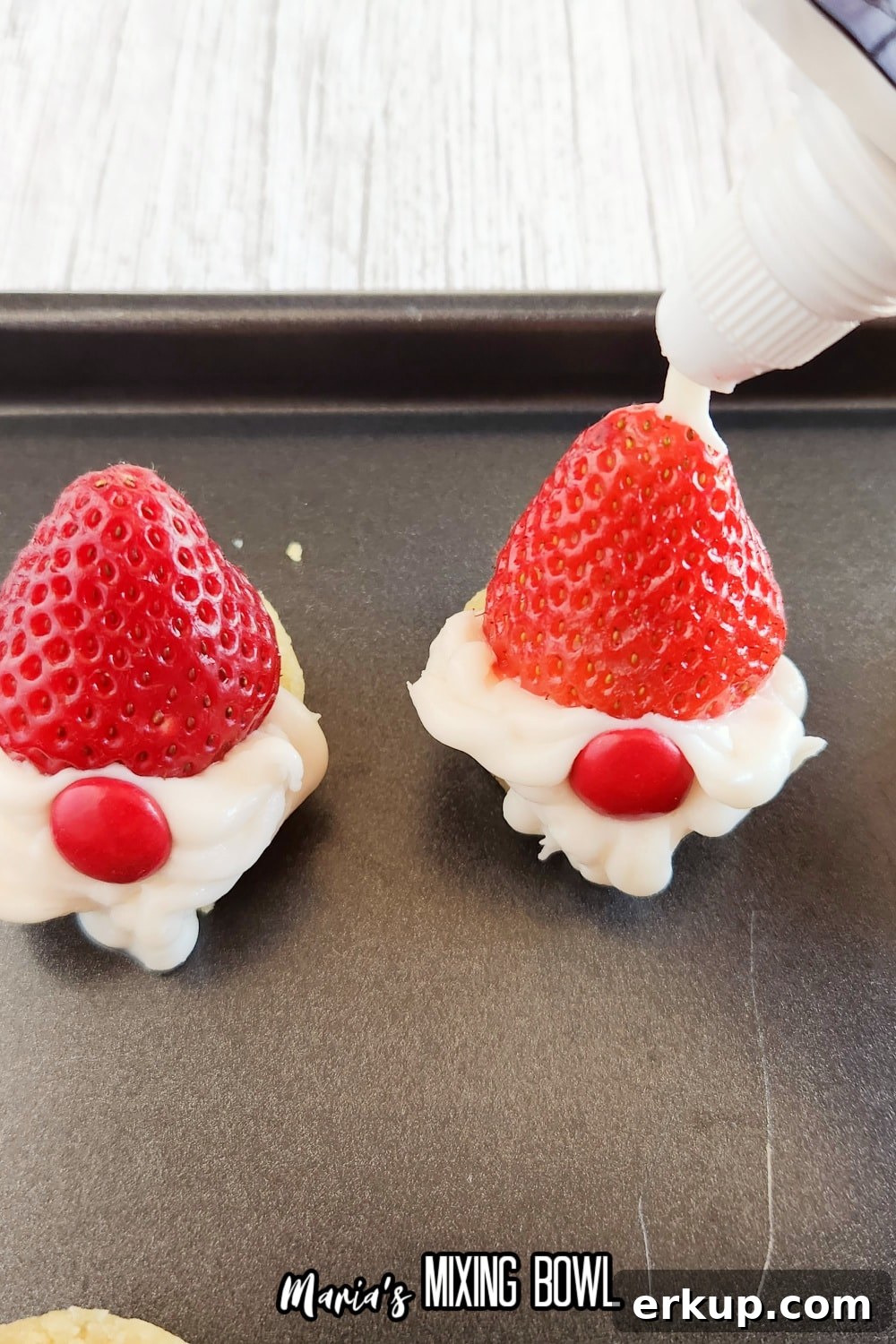 piping white icing onto a strawberry