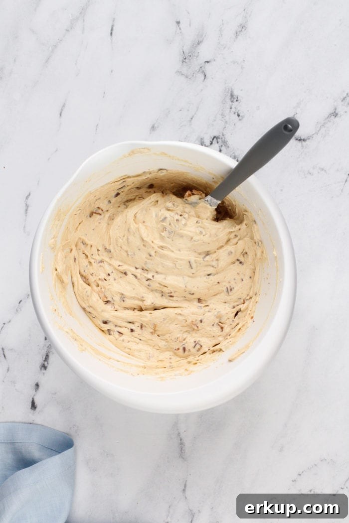 Snickers dip stirred together in a white mixing bowl.