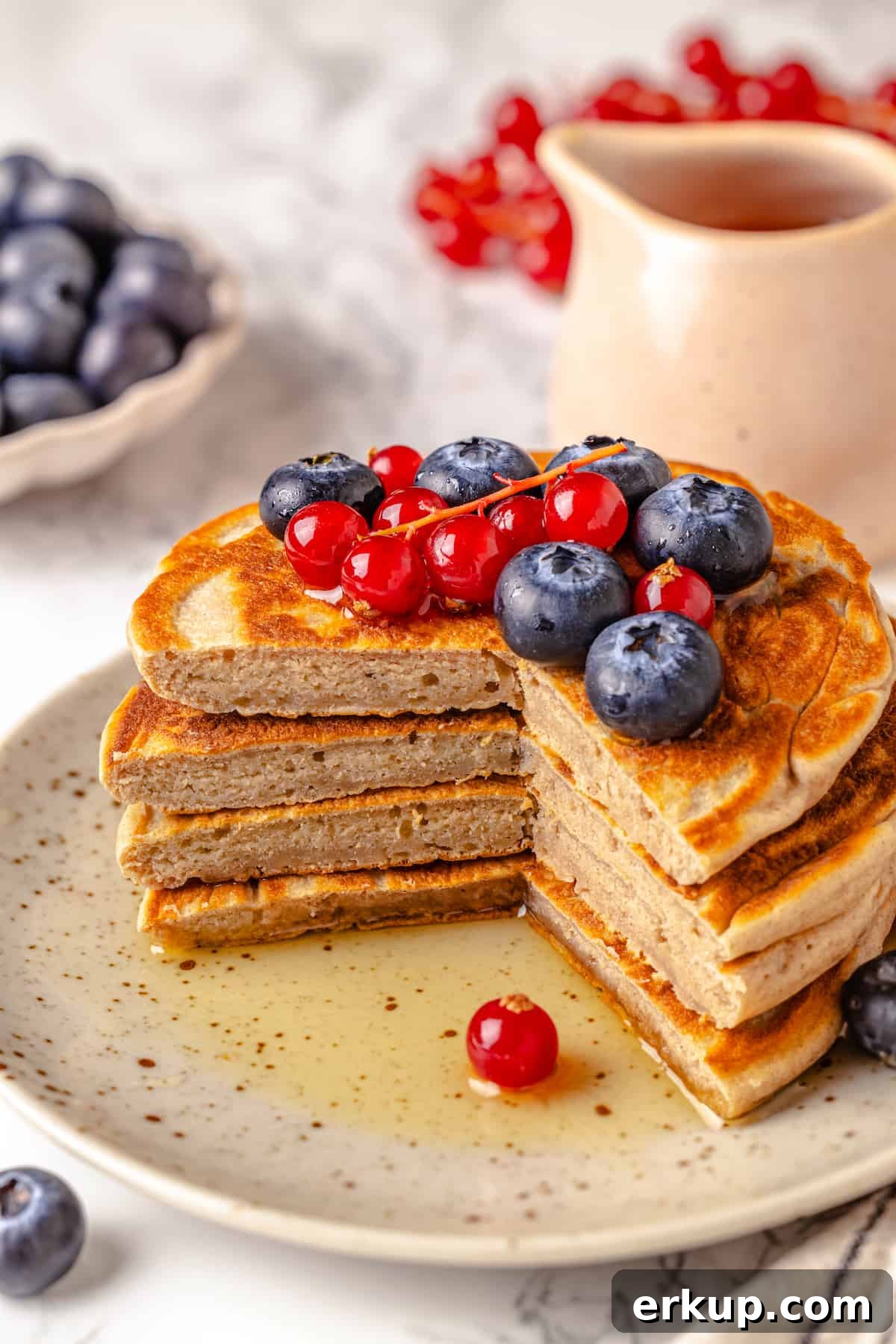 Stack of protein pancakes on plate, cut to show fluffy texture