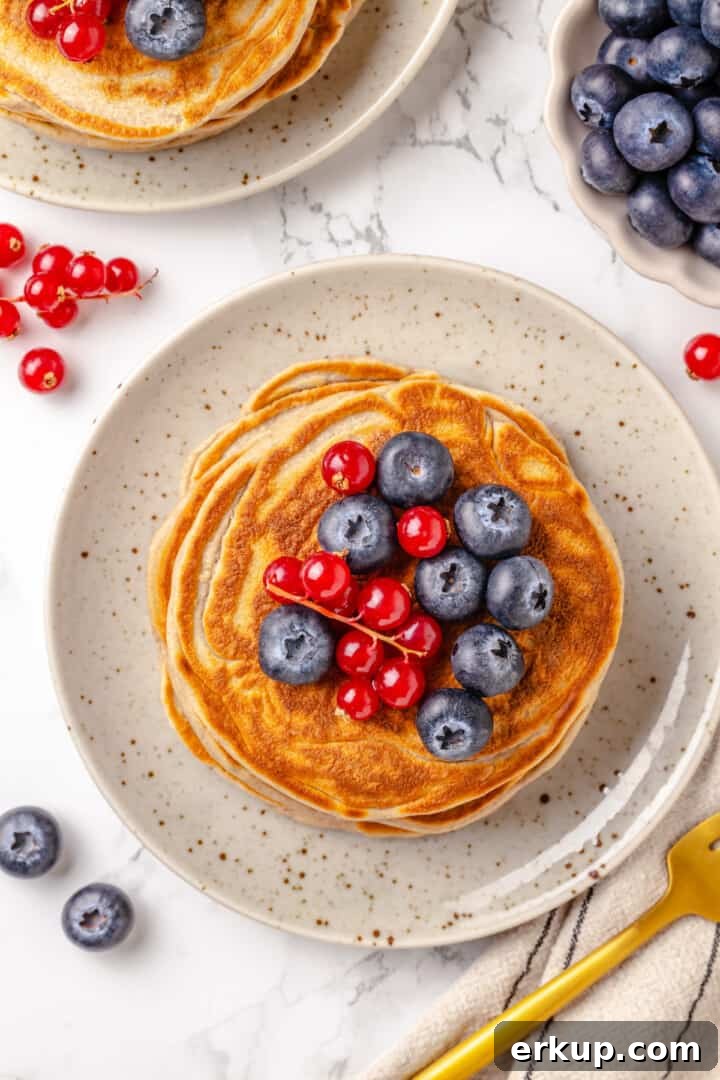 Overhead view of protein pancakes on plate with berries on top